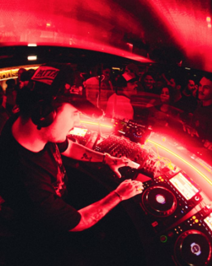 DJ playing at the MESS booth under red lights